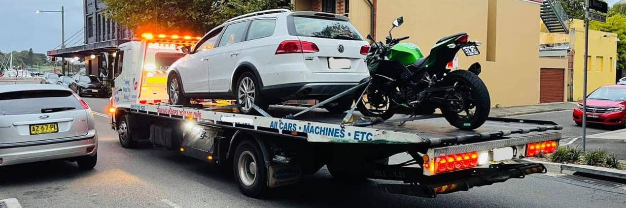 A truck with a motorbike on the back of it after also towing a car.