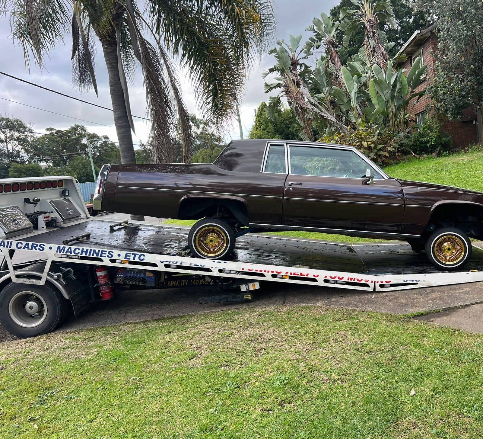 A BMW getting transported by a tilt tray tow truck.